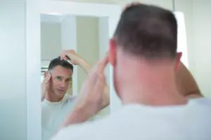 man-combs-his-hair-in-the-bathroom